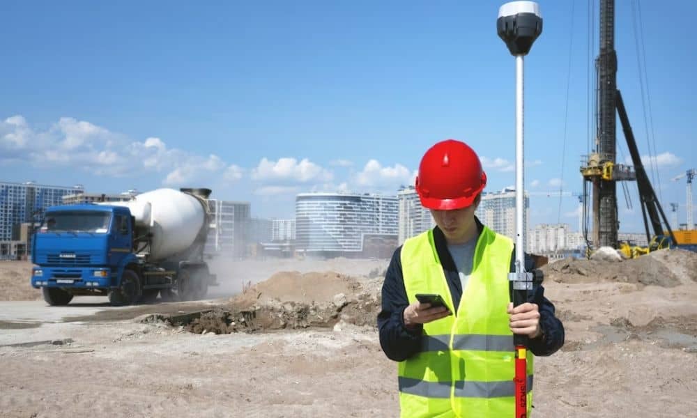 Surveyor using GPS equipment for a topographic survey on a construction site